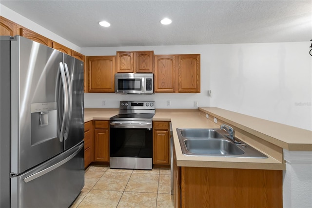 kitchen with brown cabinets, light tile patterned floors, stainless steel appliances, light countertops, and a sink