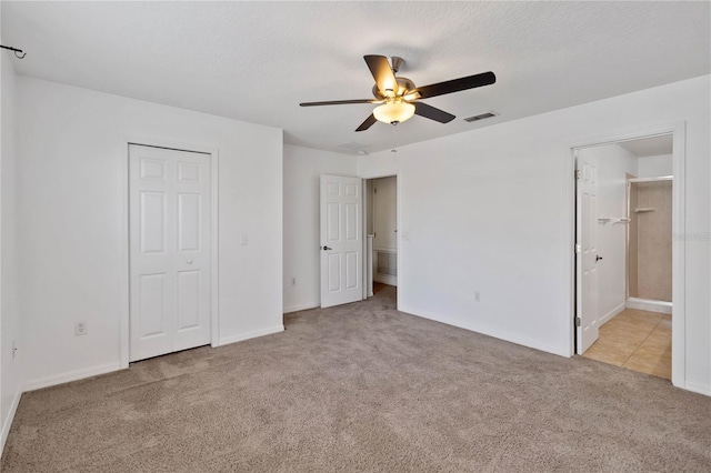 unfurnished bedroom with a textured ceiling, ceiling fan, light colored carpet, visible vents, and a closet