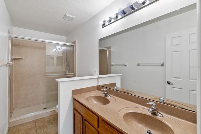 bathroom featuring a textured ceiling, a sink, toilet, and tile patterned floors