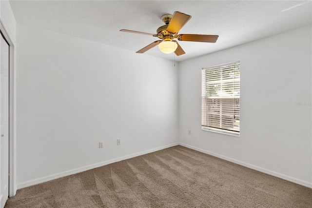 carpeted empty room featuring baseboards and a ceiling fan