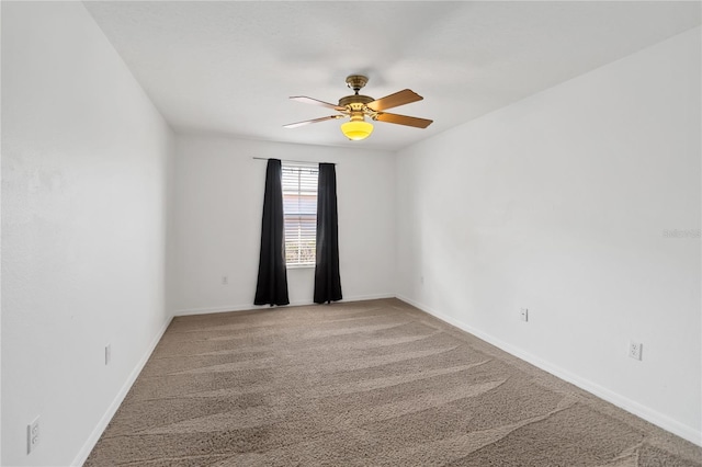 carpeted spare room featuring a ceiling fan and baseboards