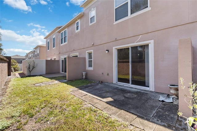 rear view of property featuring a patio area, a fenced backyard, a yard, and stucco siding