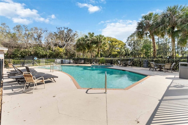 pool with a patio area and fence