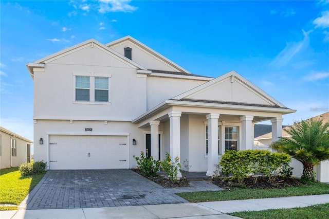 view of front of house featuring decorative driveway, an attached garage, and stucco siding