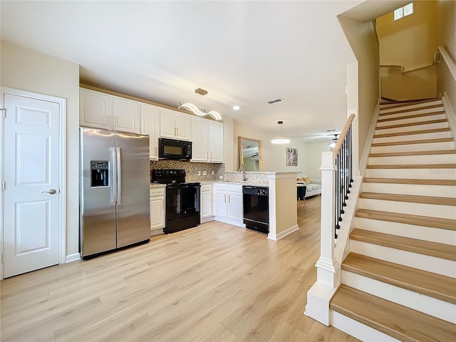 1410 Stockton Dr, Sanford, FL 32771 - kitchen with tasteful backsplash, light wood-style floors, a peninsula, light countertops, and black appliances