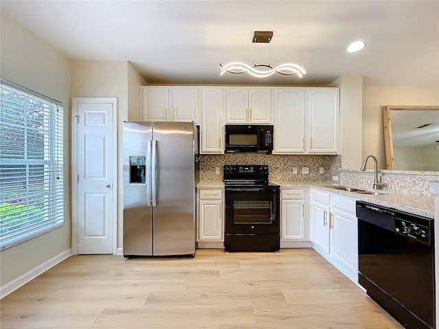 1410 Stockton Dr, Sanford, FL 32771 - kitchen with decorative backsplash, white cabinets, a sink, and black appliances