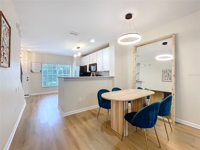 1410 Stockton Dr, Sanford, FL 32771 - kitchen with tasteful backsplash, visible vents, white cabinets, light wood-type flooring, and black appliances