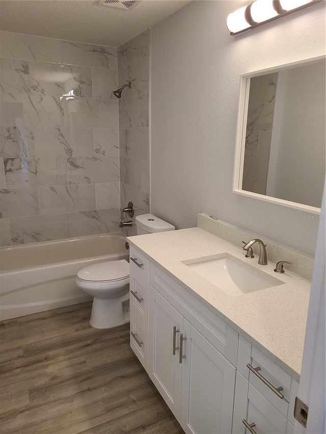 full bathroom featuring bathing tub / shower combination, visible vents, toilet, vanity, and wood finished floors