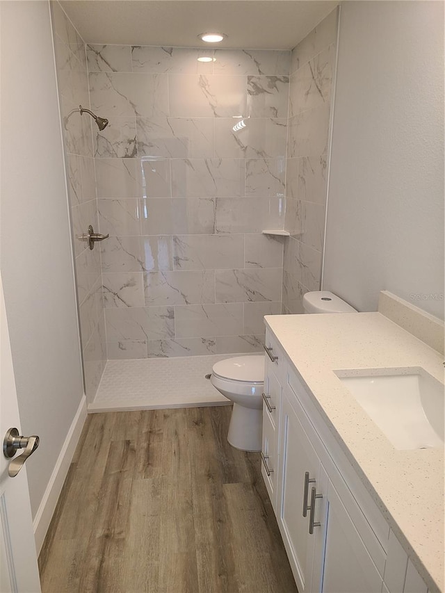 bathroom featuring baseboards, toilet, wood finished floors, vanity, and a shower stall