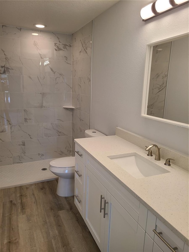 bathroom featuring toilet, a shower stall, wood finished floors, and vanity