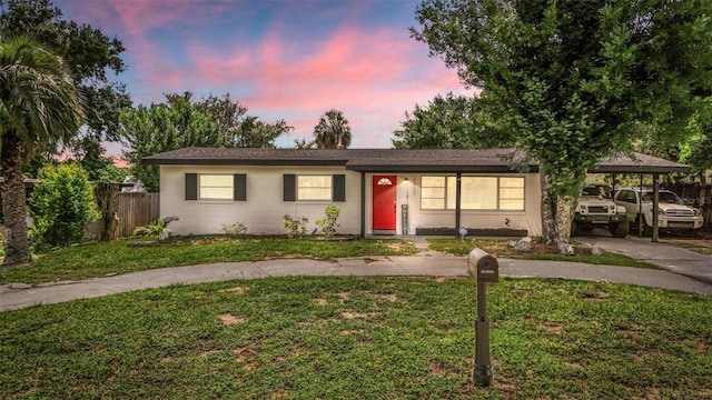 ranch-style house with a yard, driveway, and fence