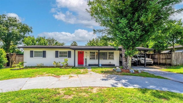 ranch-style house with a front yard, driveway, an attached carport, and fence