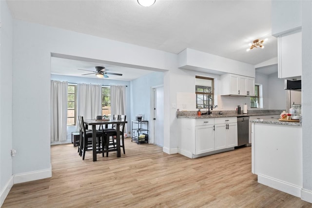 kitchen featuring light wood finished floors, baseboards, white cabinetry, and stainless steel dishwasher