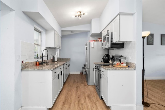 kitchen featuring stainless steel appliances, white cabinets, a sink, and light wood-style flooring