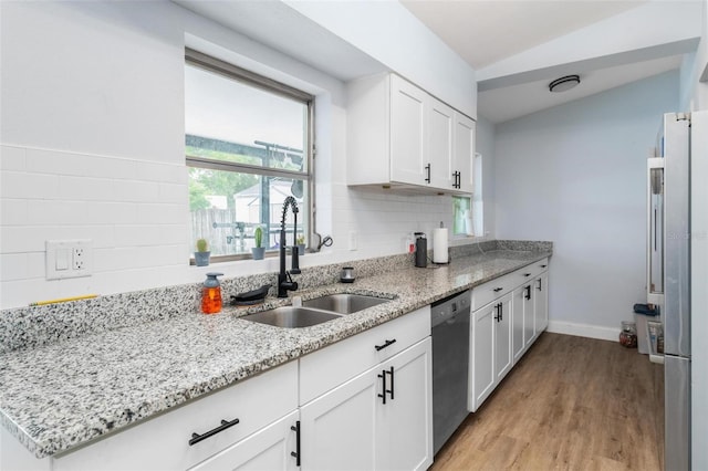 kitchen with lofted ceiling, stainless steel appliances, a sink, white cabinetry, and light wood finished floors