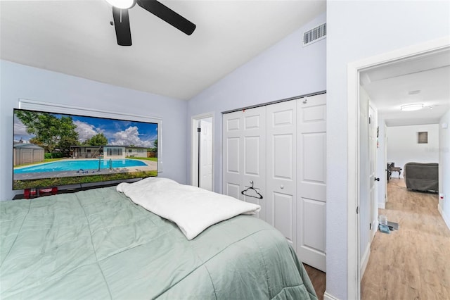 bedroom with lofted ceiling, a closet, visible vents, ceiling fan, and wood finished floors