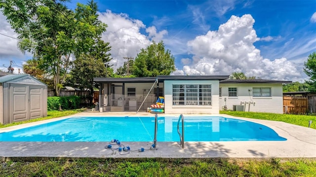 rear view of house with a fenced in pool, a sunroom, fence, a storage unit, and an outdoor structure