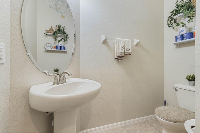 half bathroom with baseboards, toilet, and tile patterned floors