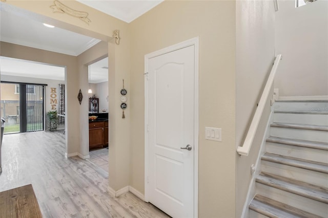 stairway featuring crown molding, baseboards, and wood finished floors