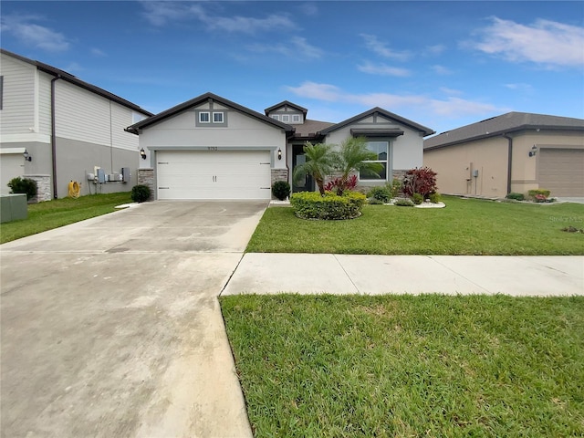 view of front of property featuring stone siding, a front yard, concrete driveway, and stucco siding