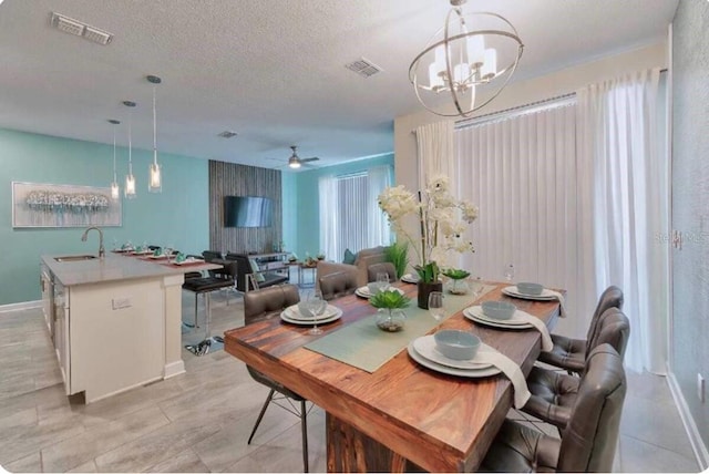 dining area with baseboards, visible vents, a textured ceiling, and ceiling fan with notable chandelier