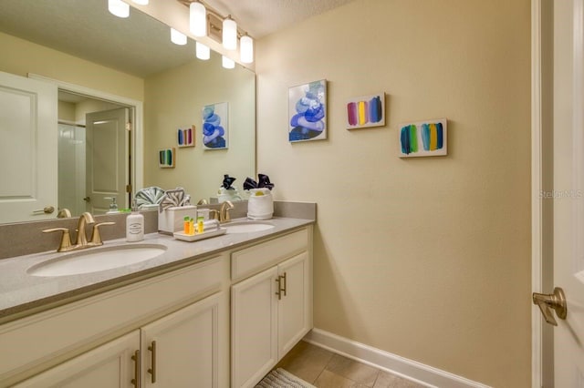 bathroom featuring a sink, a textured ceiling, baseboards, and double vanity