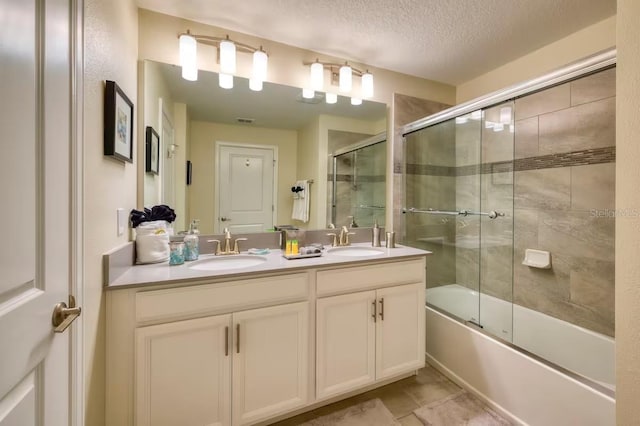 bathroom featuring double vanity, a textured ceiling, enclosed tub / shower combo, and a sink