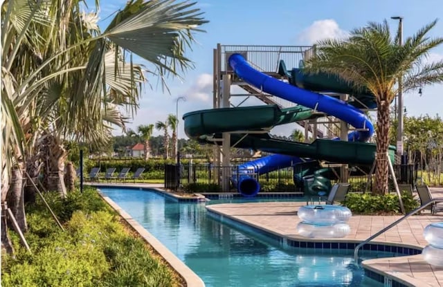 view of swimming pool with a water slide and fence