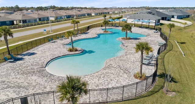 view of pool featuring a lawn, fence, and a residential view