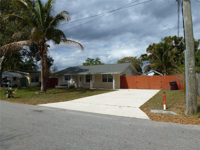 ranch-style home with driveway, a gate, fence, a front lawn, and stucco siding