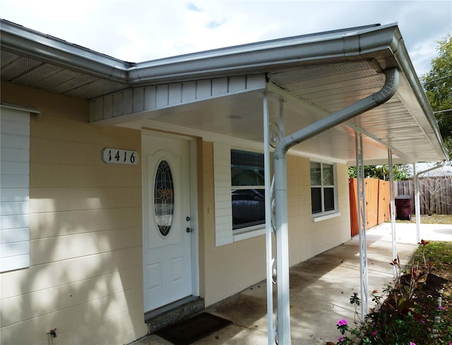 doorway to property featuring fence and a carport