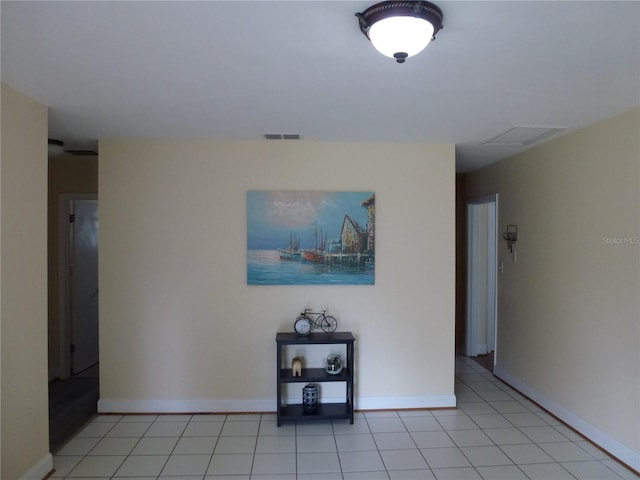 corridor featuring visible vents, baseboards, and light tile patterned floors