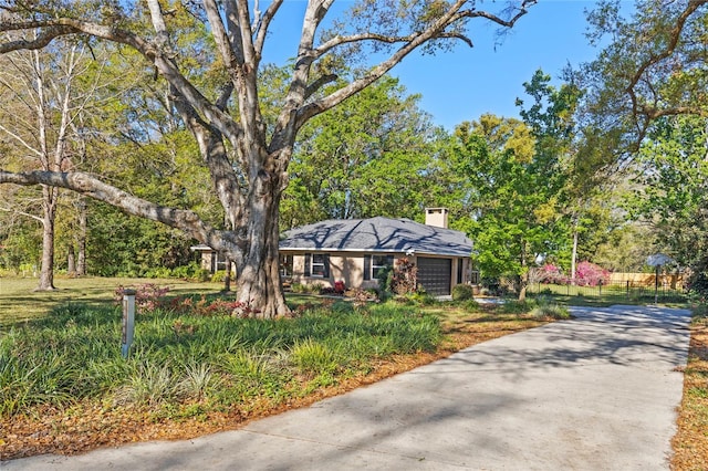 view of front facade featuring a chimney, concrete driveway, and an attached garage