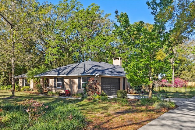 view of front of property with fence, driveway, an attached garage, a chimney, and a front lawn