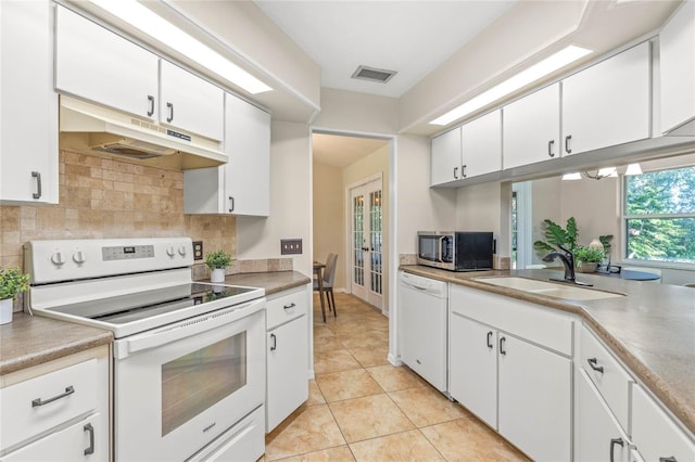 kitchen featuring visible vents, under cabinet range hood, a sink, white appliances, and decorative backsplash