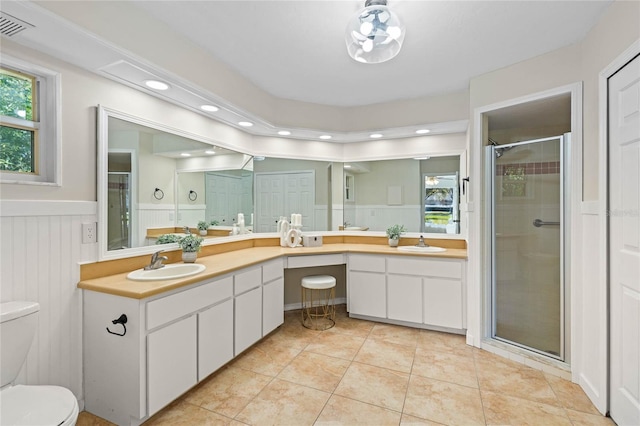 full bathroom with wainscoting, toilet, a shower stall, and a sink