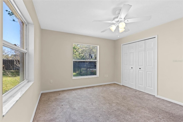 unfurnished bedroom featuring a closet, baseboards, carpet, and a ceiling fan