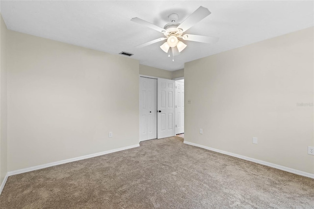 carpeted spare room with a ceiling fan, baseboards, and visible vents