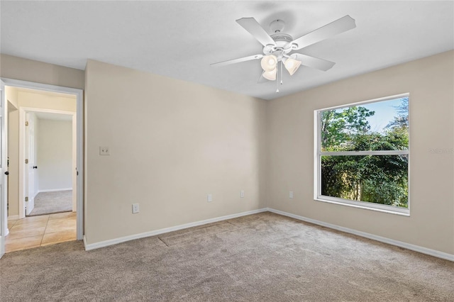 carpeted spare room featuring baseboards and a ceiling fan