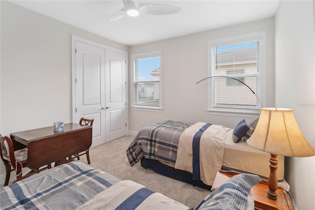 bedroom with light carpet, ceiling fan, a closet, and baseboards