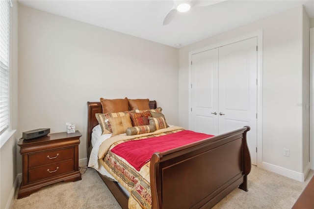 bedroom featuring a closet, light colored carpet, ceiling fan, and baseboards