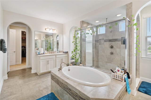 full bath featuring vanity, baseboards, a spacious closet, tiled shower, and a bath