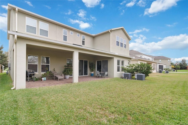 rear view of house with a yard, central AC, a patio area, and stucco siding