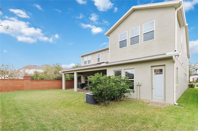 rear view of property featuring a yard, a patio area, fence, and stucco siding