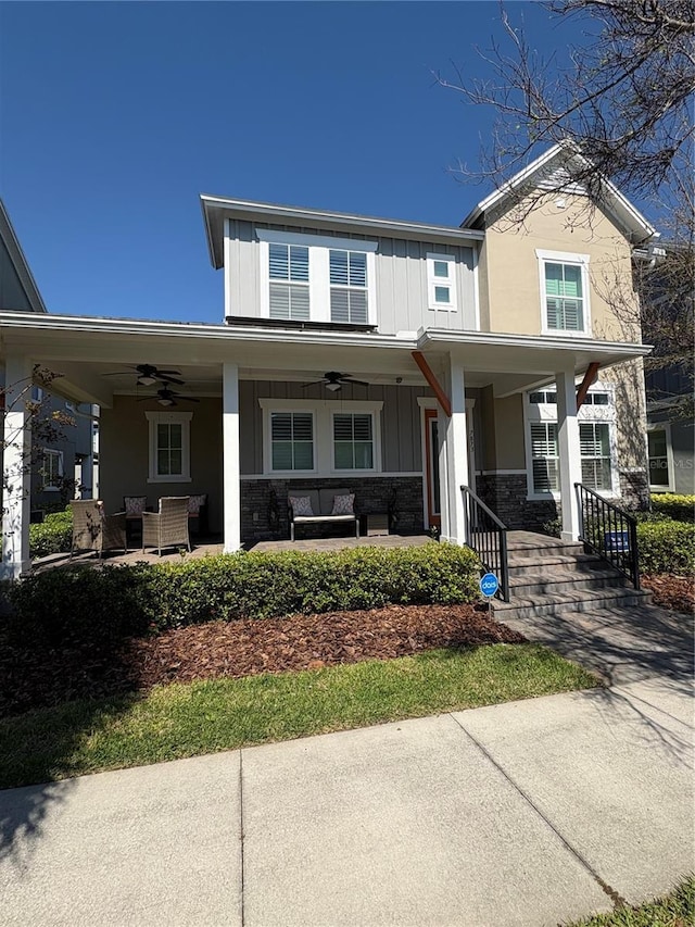 view of front of home featuring stone siding, ceiling fan, a porch, and board and batten siding