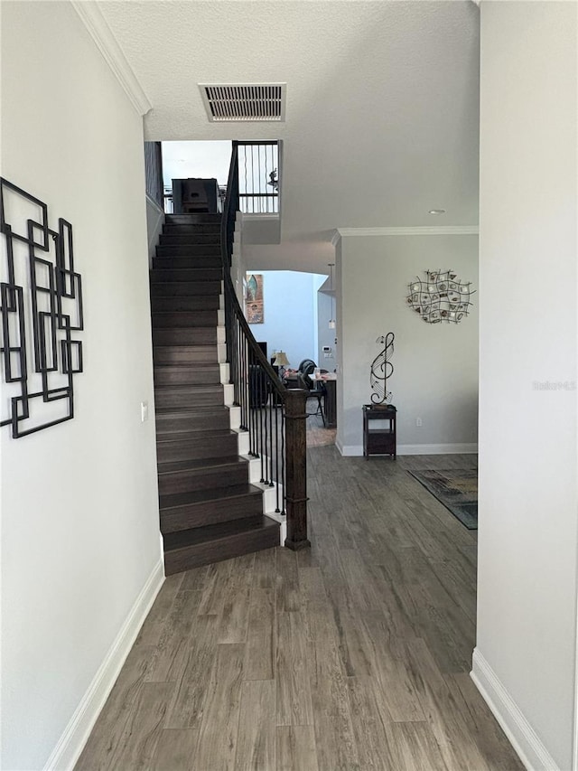 interior space featuring visible vents, crown molding, stairway, and wood finished floors