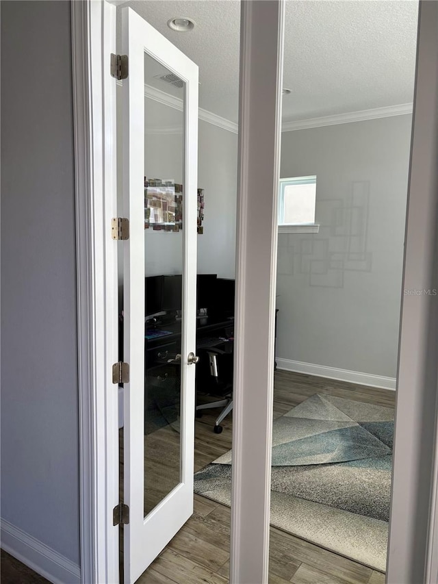 interior space with french doors, crown molding, a textured ceiling, and wood finished floors