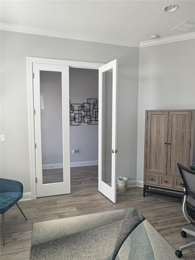 bedroom with crown molding, visible vents, wood finished floors, and french doors