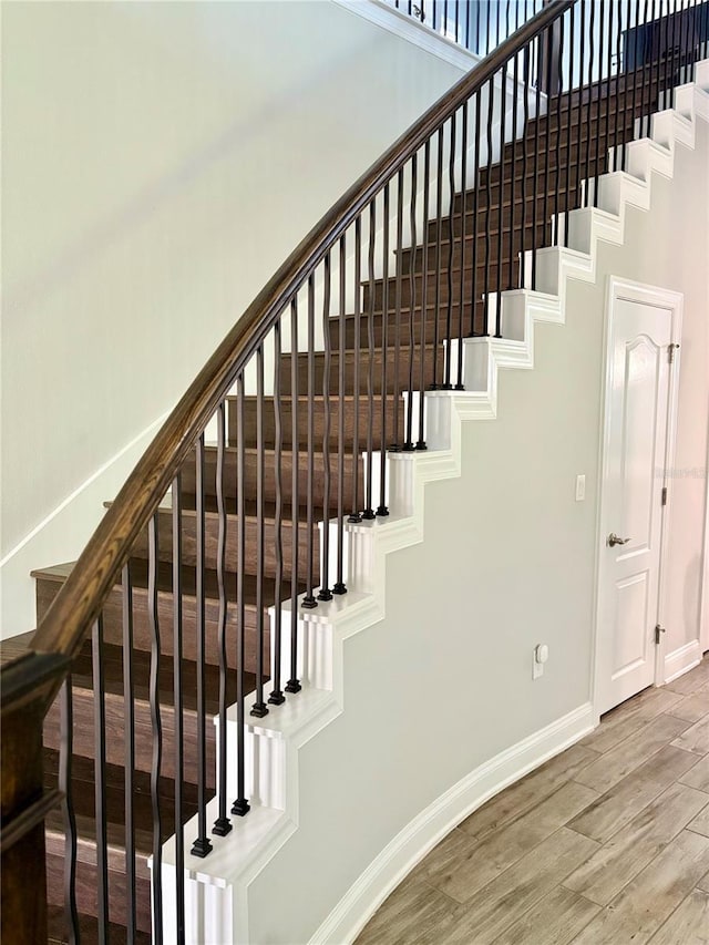 stairs featuring a high ceiling, baseboards, and wood finished floors