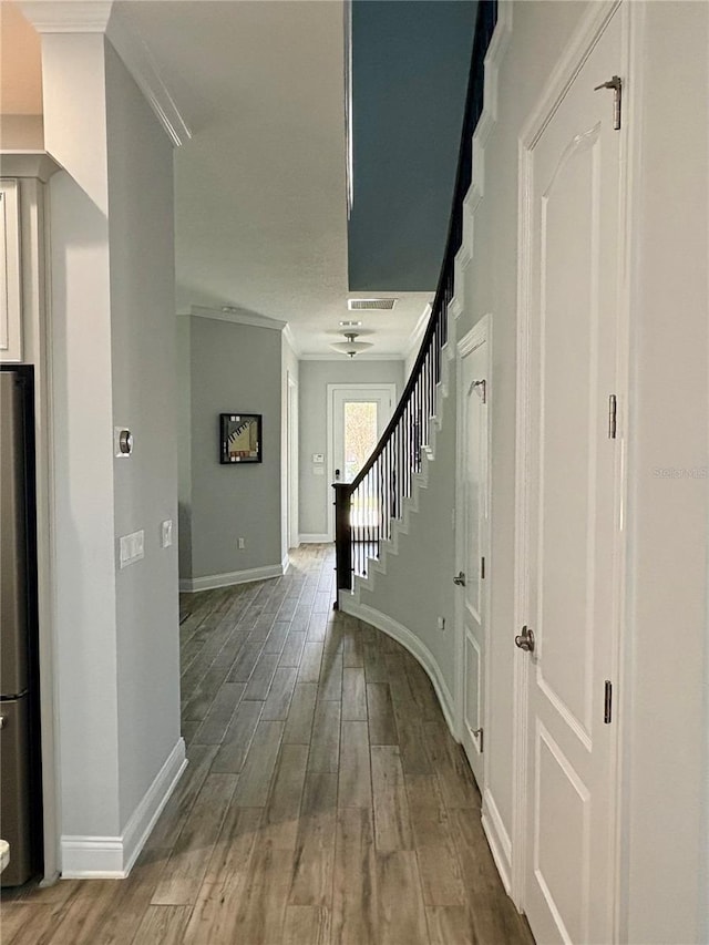 hall with stairs, crown molding, baseboards, and wood finished floors